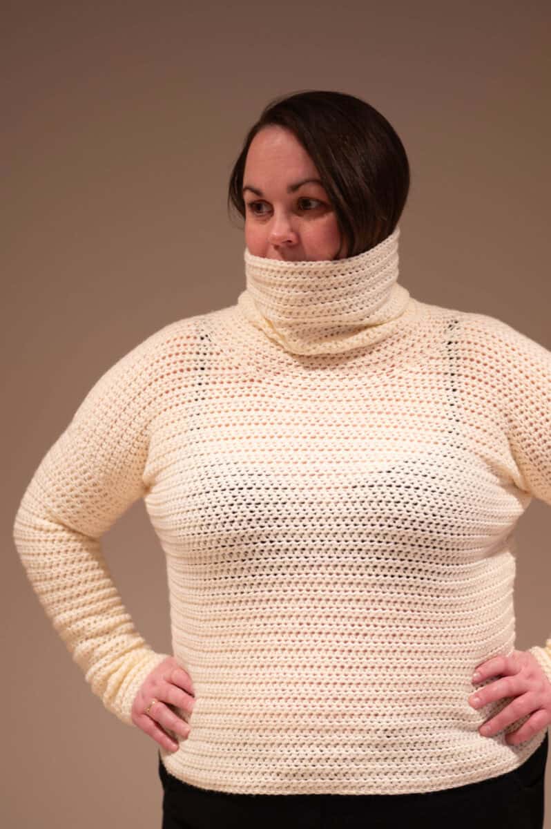 Off-white crochet cowl neck sweater made with light yarn, featuring a textured stitch pattern.